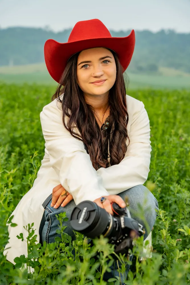 A woman sitting in the grass with a camera.