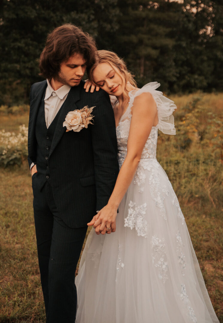 A man and woman holding hands in the grass.