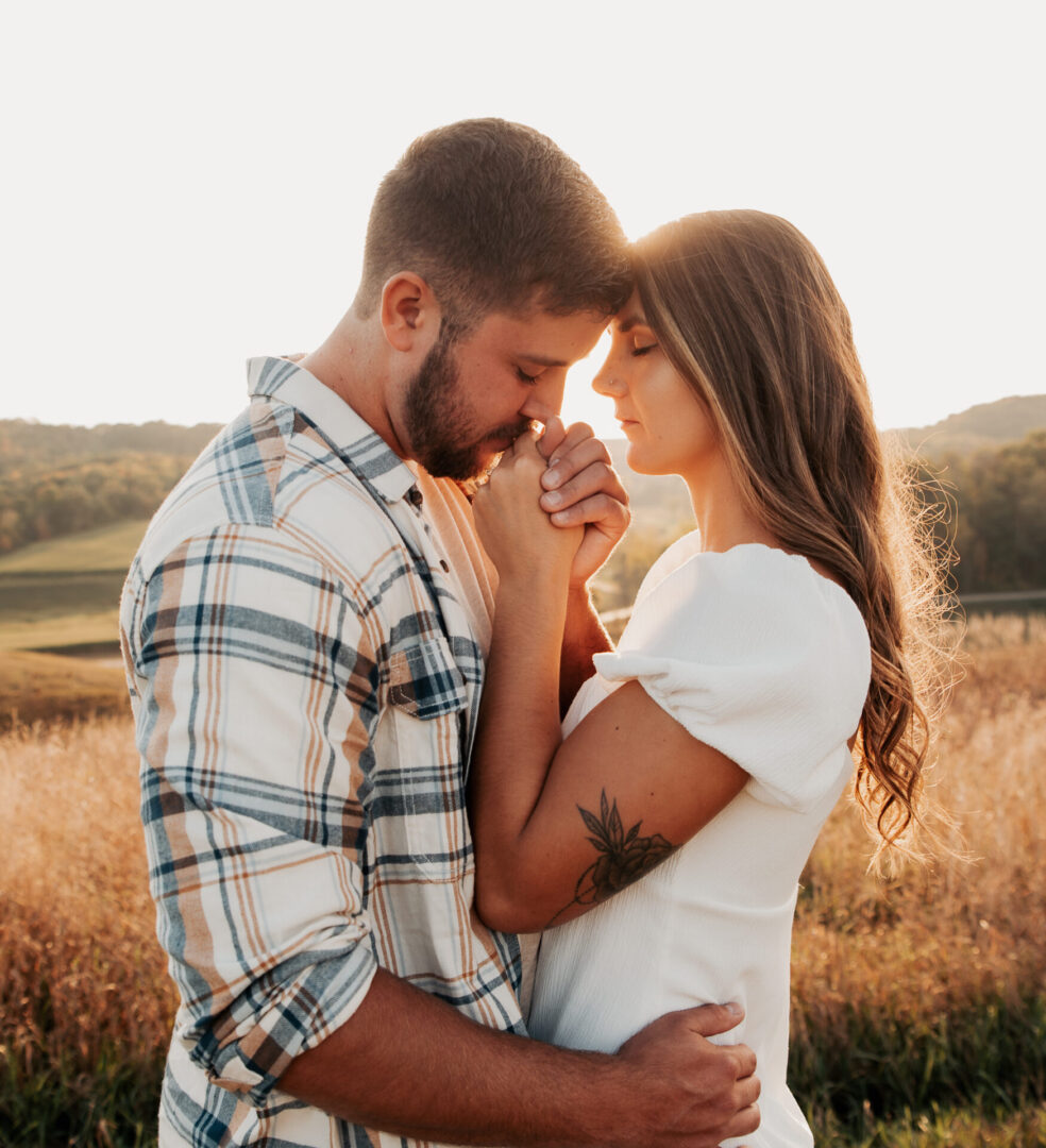 A man and woman embracing in the middle of a field.