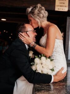 A bride and groom kissing in front of the camera.