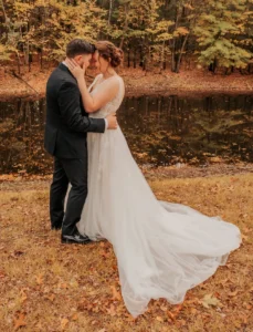 A man and woman kissing in front of a body of water.