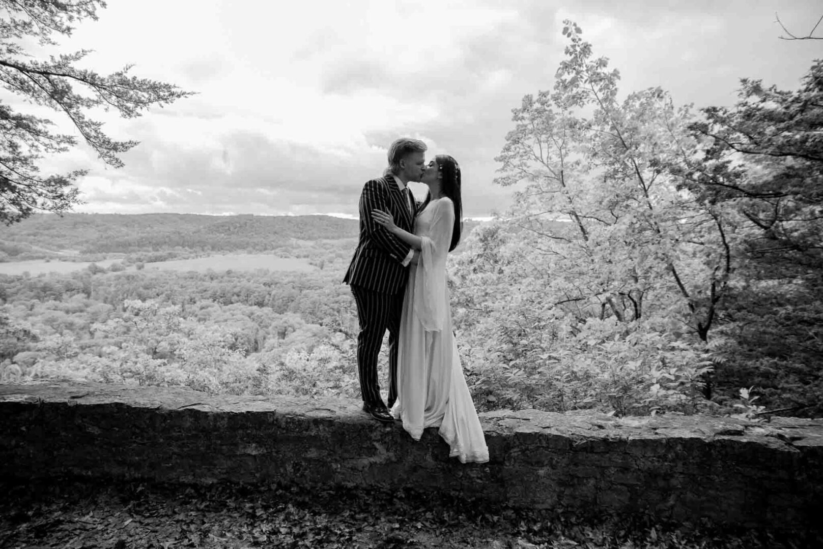 A man and woman kissing on top of a hill.