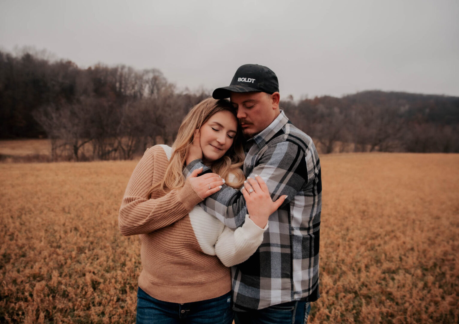 A man and woman hugging in an open field.