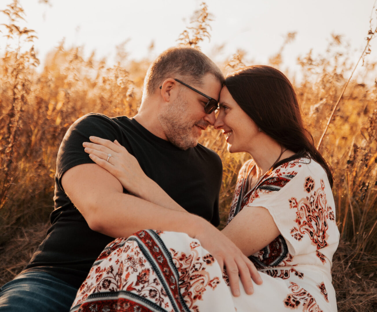 A man and woman are hugging in the field.