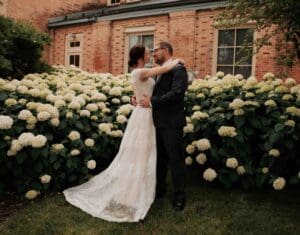 A bride and groom standing in front of some flowers