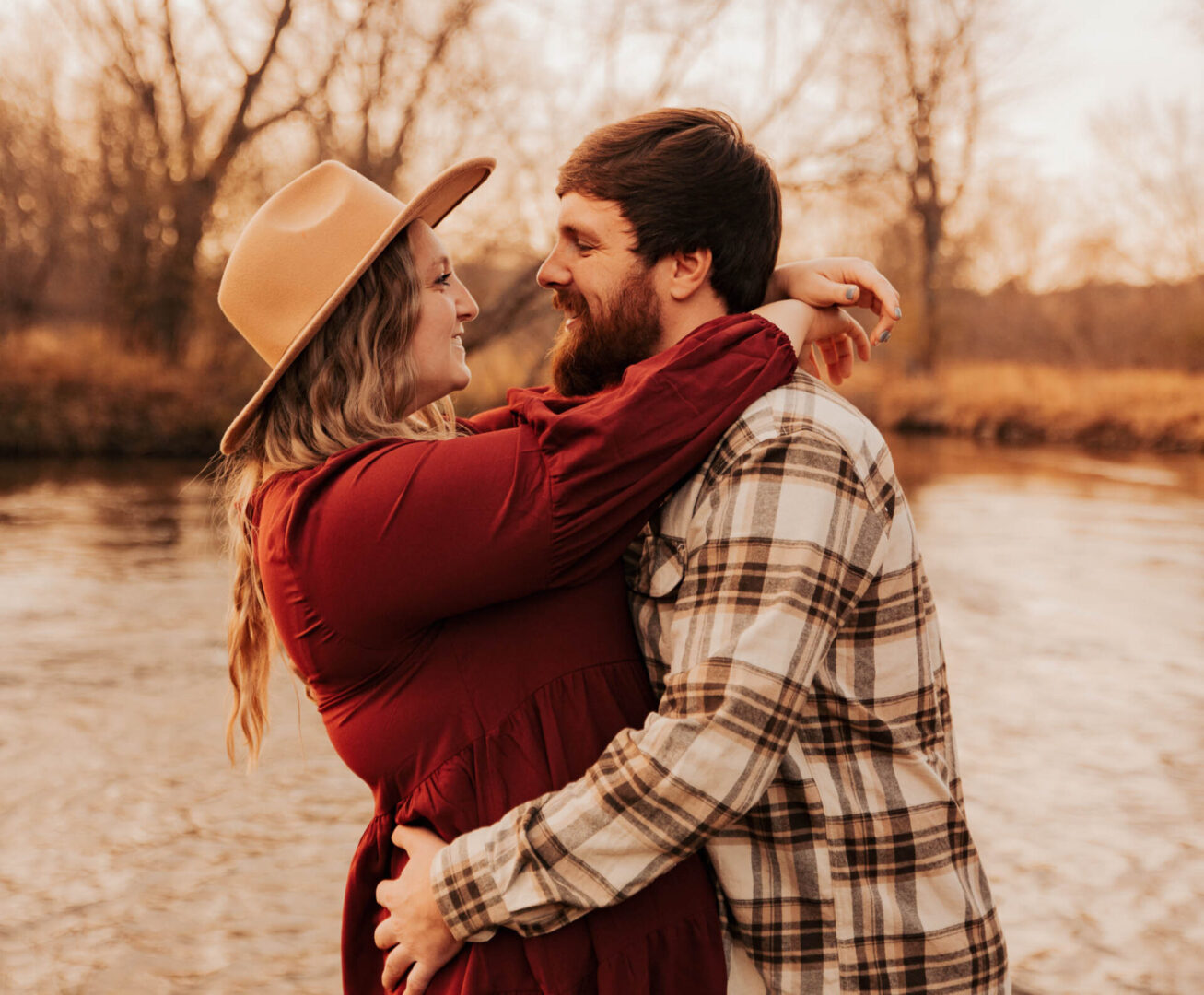 A man and woman hugging near the water.