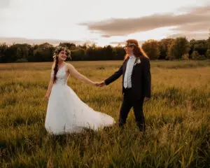 A man and woman holding hands in the middle of a field.