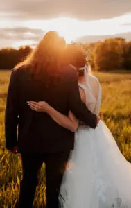 A bride and groom kissing in the middle of a field.