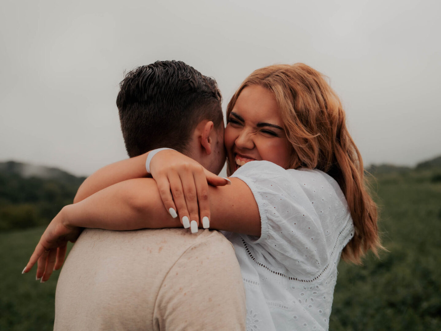 A man and woman hugging each other in the mountains.