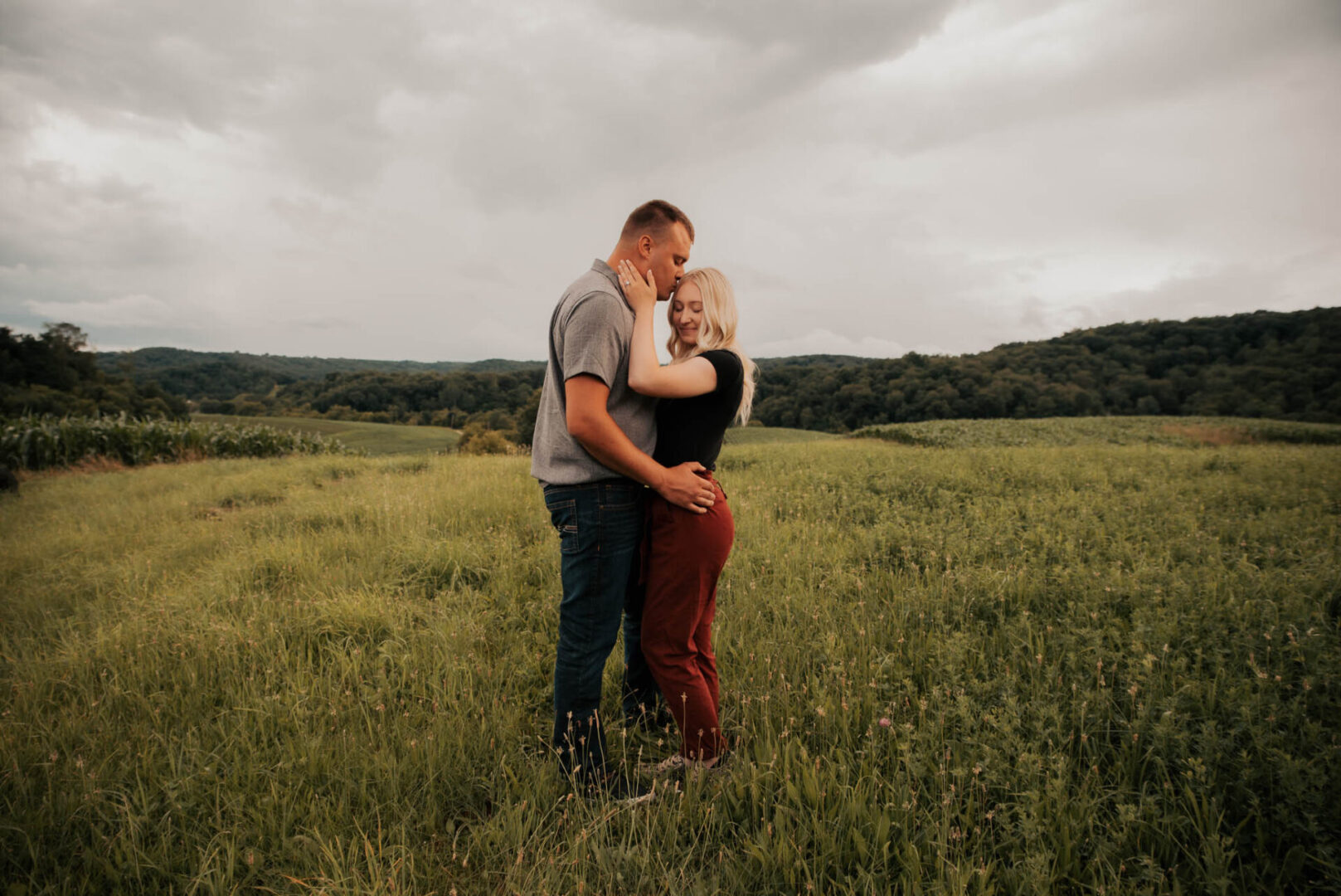 A man and woman hugging in the middle of a field.