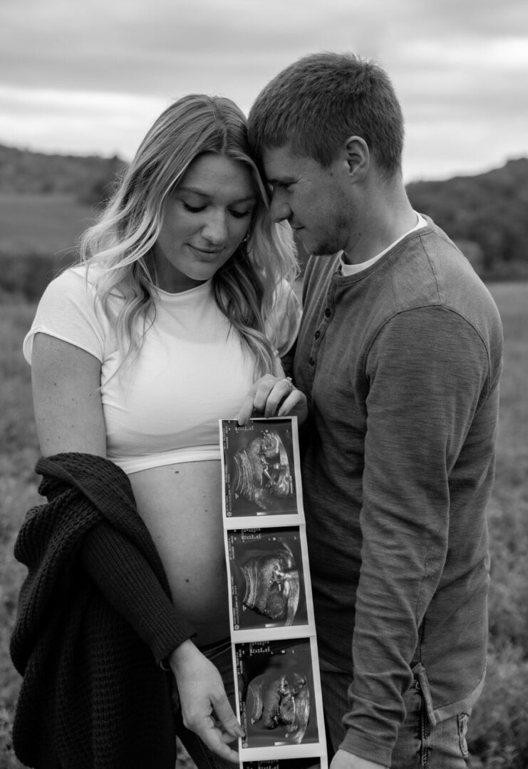 A man and woman holding up a picture of their baby.