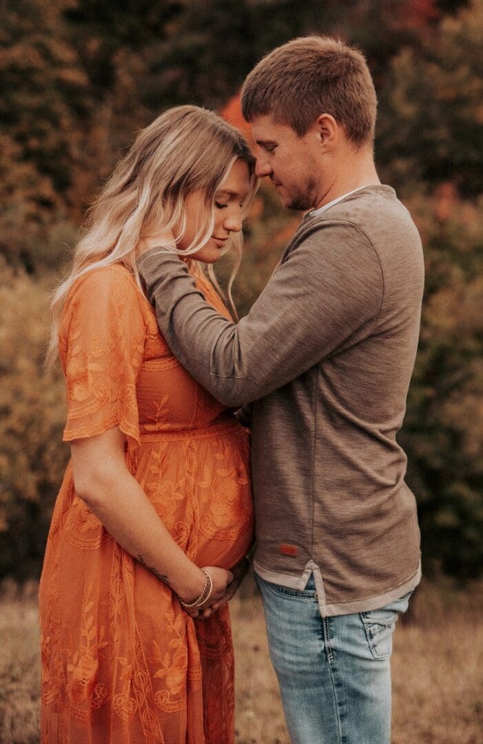 A man and woman holding hands in front of trees.