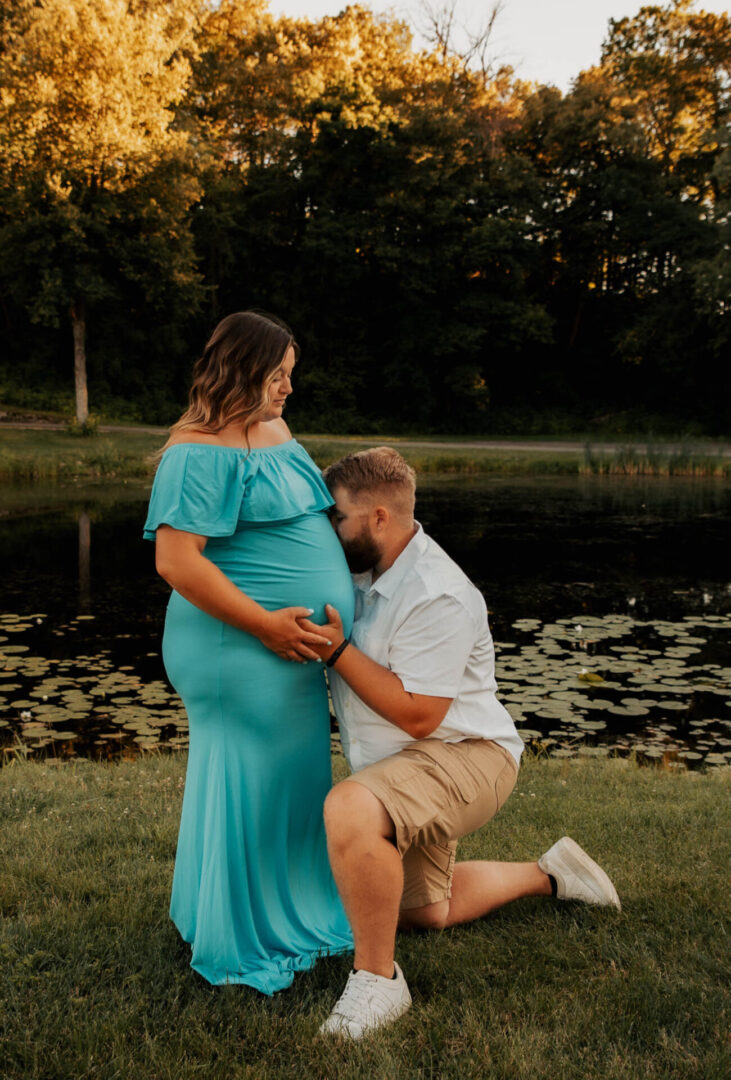 A man kneeling down next to a pregnant woman.