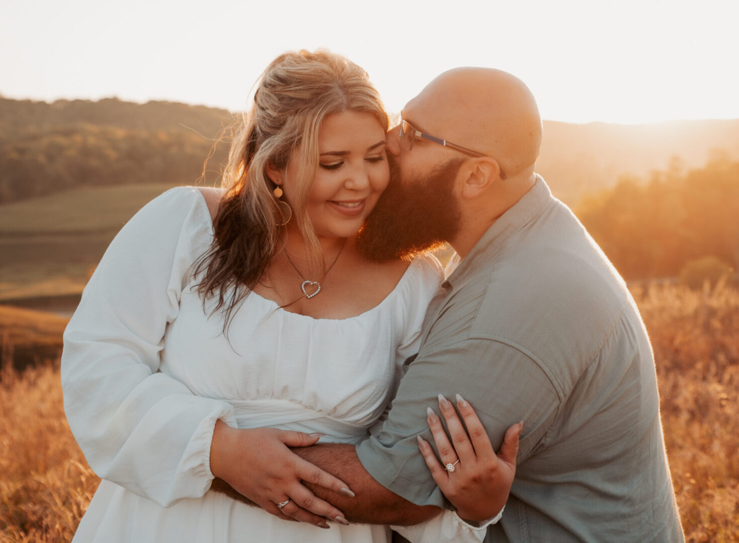 A man and woman kissing in front of the sun.