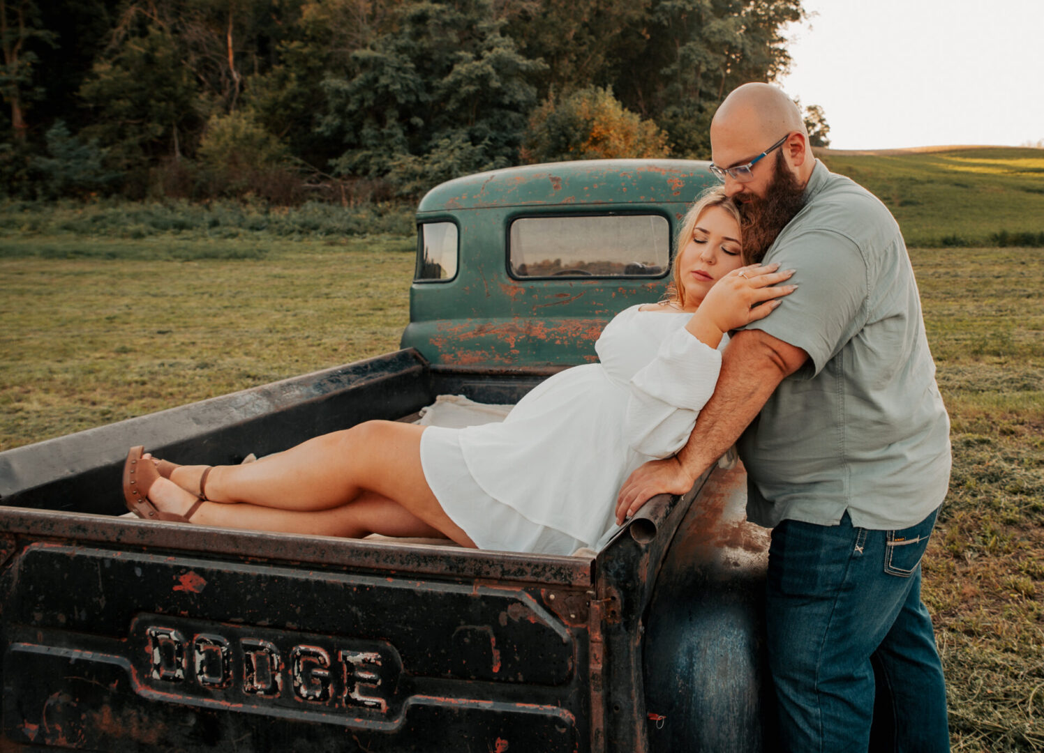 A man and woman in white dress sitting on the back of an old truck.