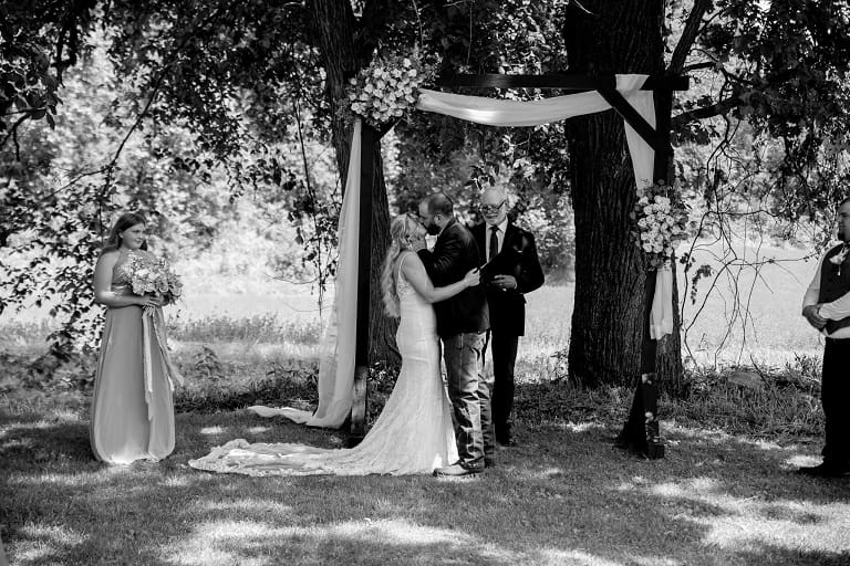 A man and woman standing under an arbor.