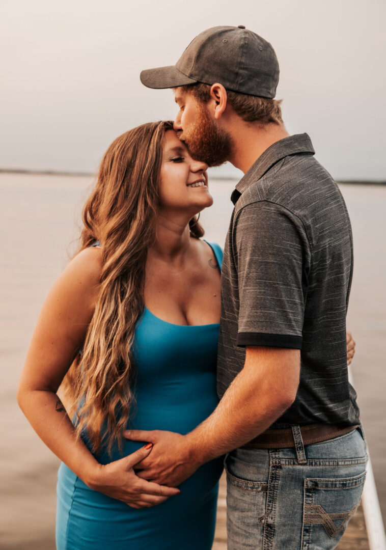 A man and woman kissing on the beach.