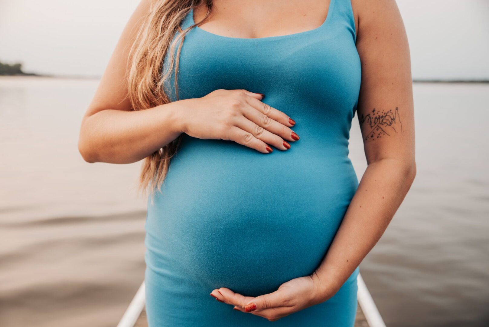 A pregnant woman holding her belly in front of the camera.