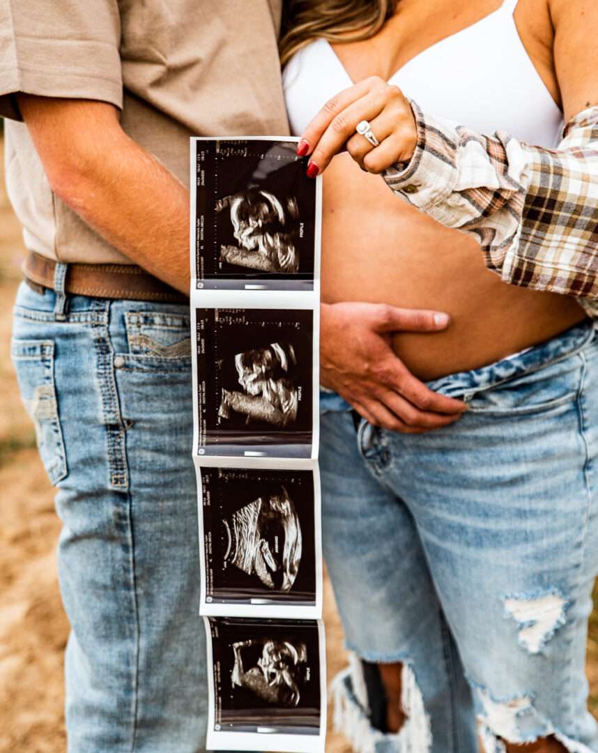 A man and woman holding up a photo of their baby.