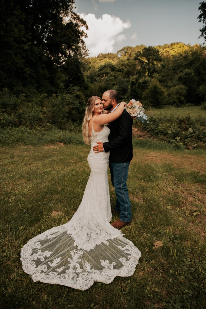 A bride and groom kissing in the grass.