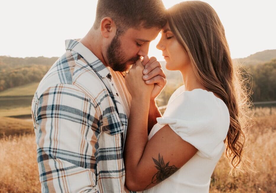 A man and woman embracing in the middle of a field.