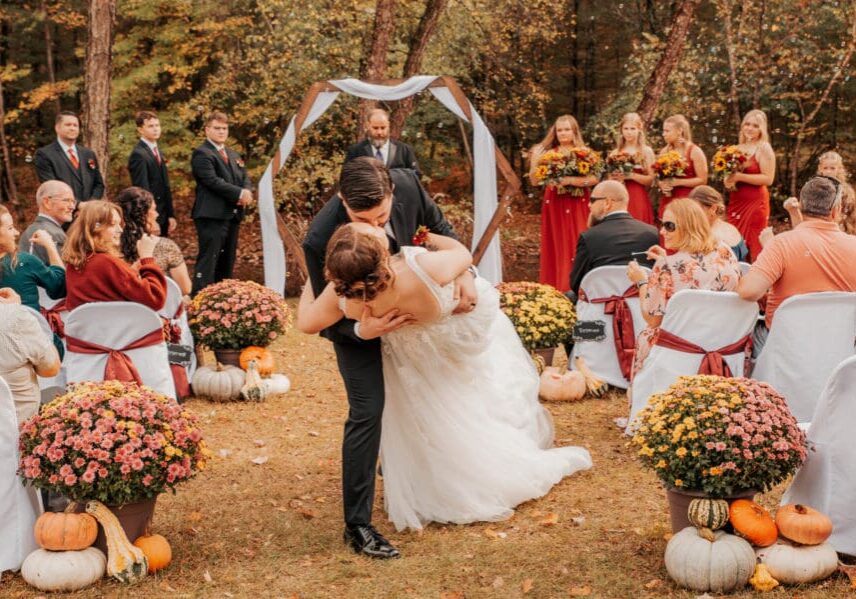 A bride and groom kissing in front of an outdoor wedding.